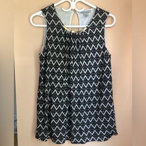 Black and white tank blouse with gold me tail detail in front.